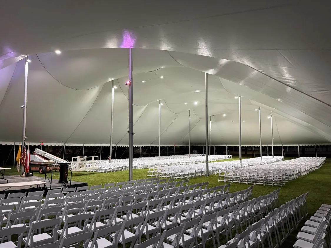 High tension fabric tent lit for an evening festival event with rows of seating